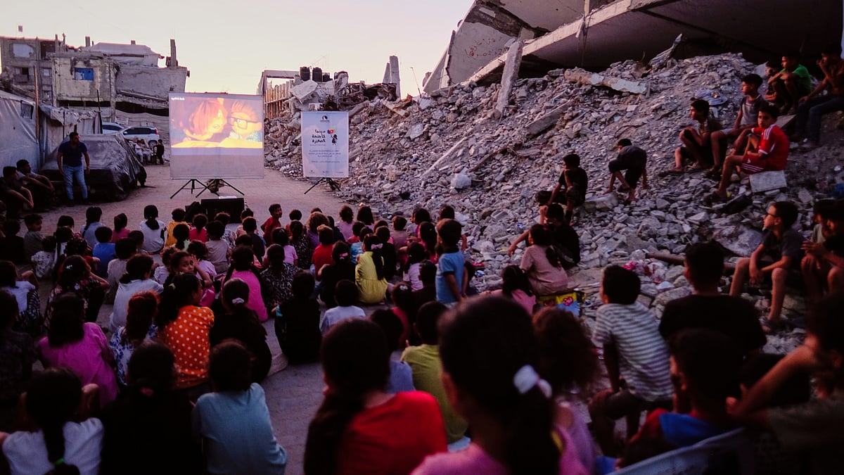 Children watch a movie amid the ruins of buildings destroyed by Israeli airstrikes in Gaza City, 8 Sep