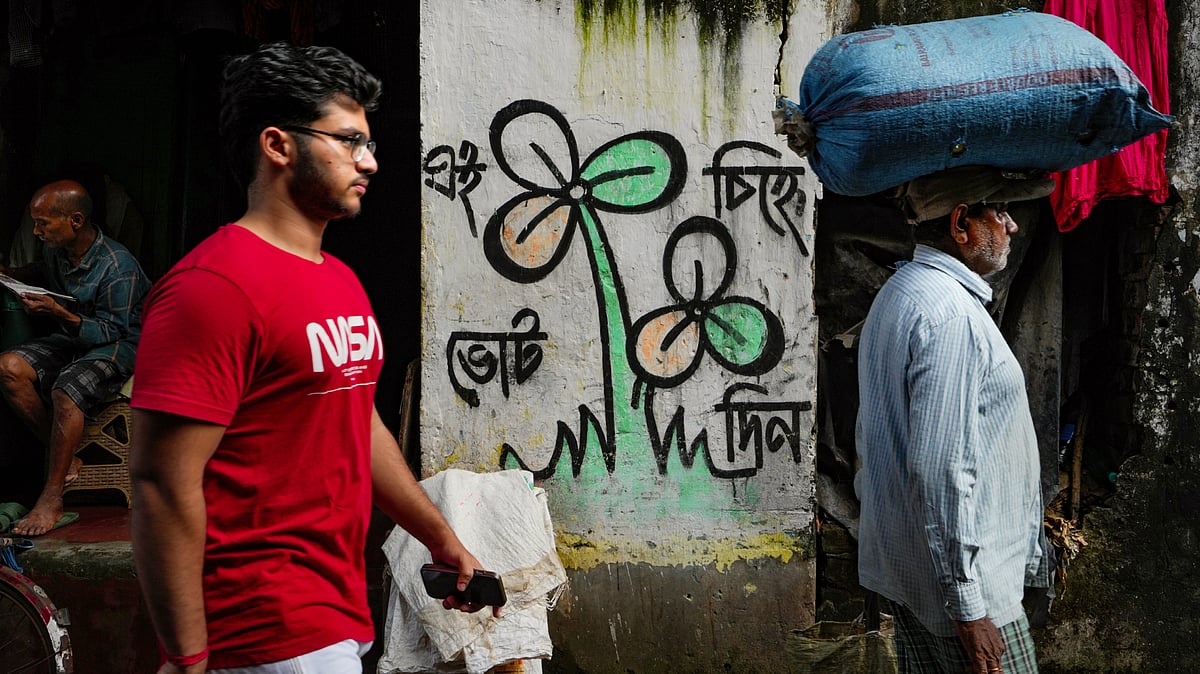 People pass by the old TMC symbol drawn on a wall in Kolkata's Kalighat area, 18 Sep