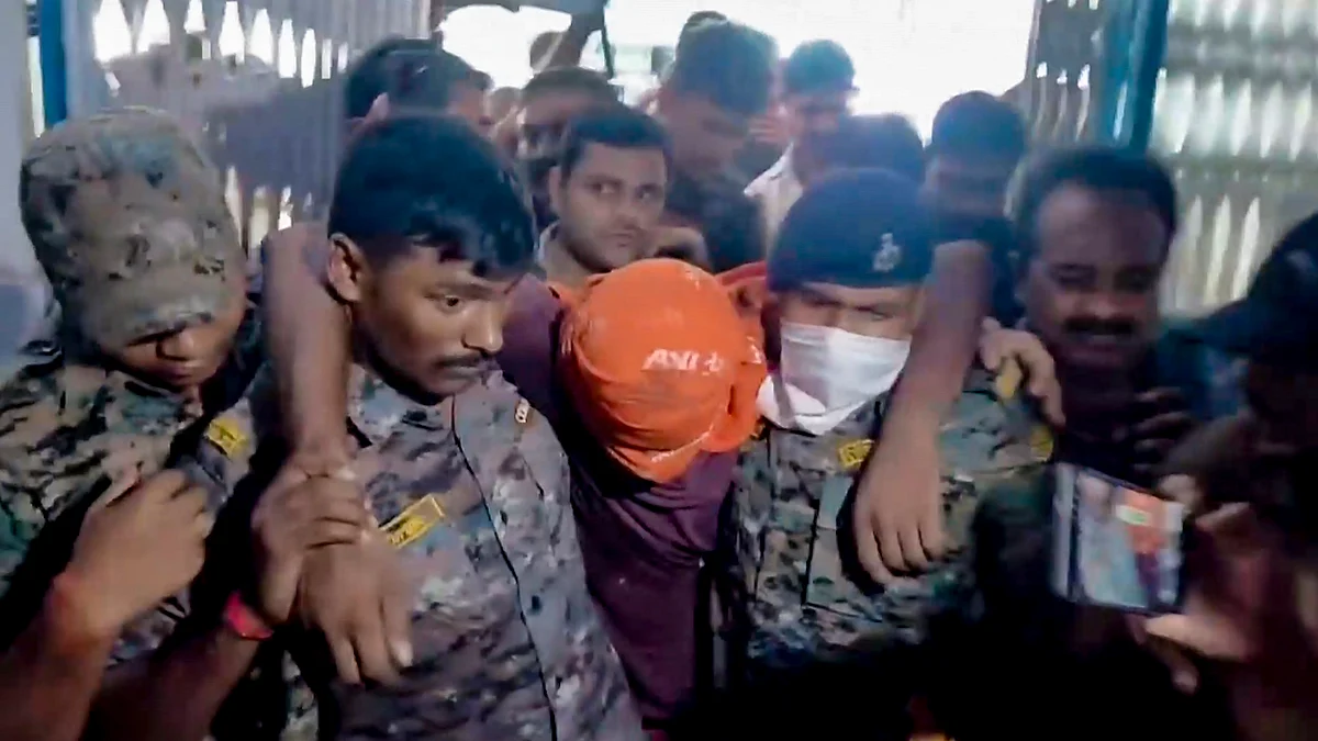 Security personnel carry an accused involved in the harassment of a boy and a girl by the roadside.