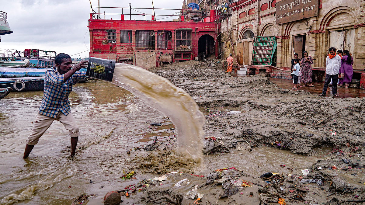 A man clears silt and mud at Varanasi's Dashashwamedh Ghat after Ganga waters receded, 24 Sep