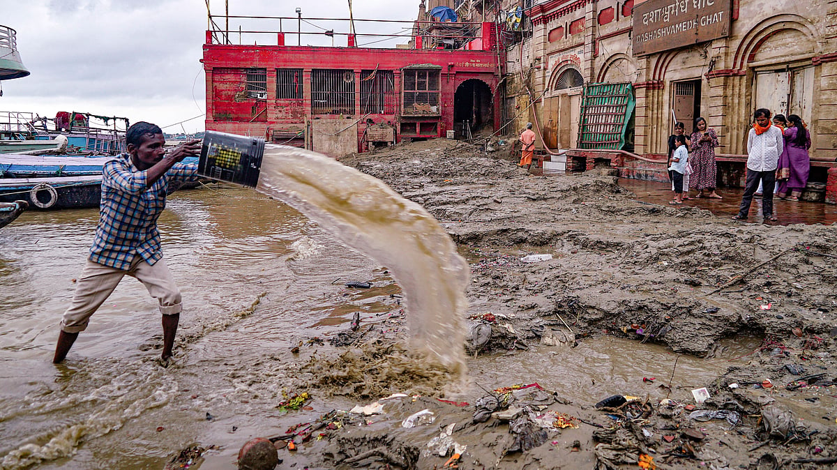 A man clears silt and mud at Varanasi's Dashashwamedh Ghat after Ganga waters receded, 24 Sep
