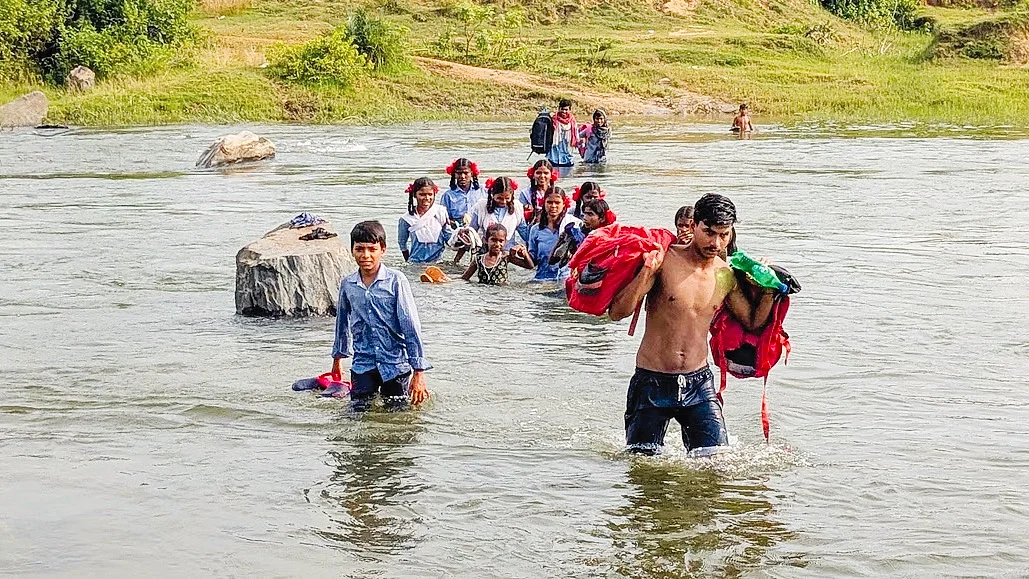 Young parent Ruben Soren helping schoolchildren across the Kiul river;