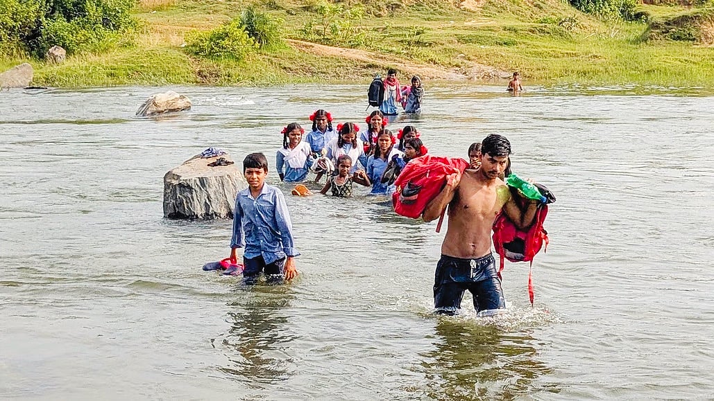 Young parent Ruben Soren helping schoolchildren across the Kiul river;