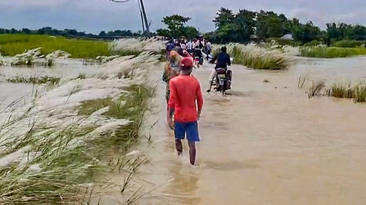 People wade through floodwaters after the Kosi river rises in Supaul district.
