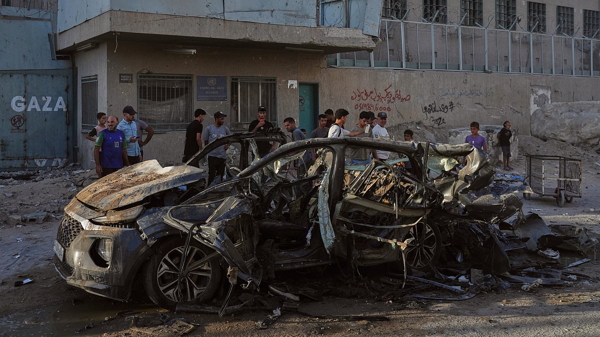 Palestinians inspect the wreckage of a car after it was hit by an Israeli strike in Gaza City.