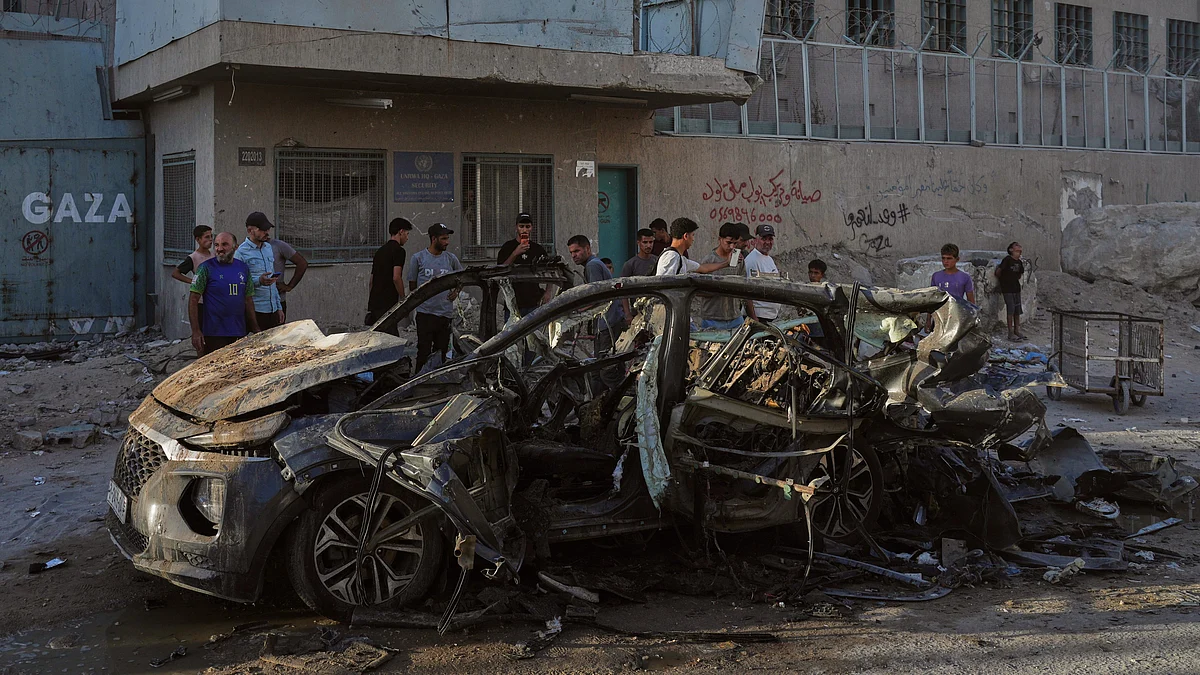 Palestinians inspect the wreckage of a car after it was hit by an Israeli strike in Gaza City.