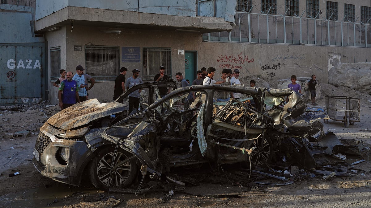 Palestinians inspect the wreckage of a car after it was hit by an Israeli strike in Gaza City.