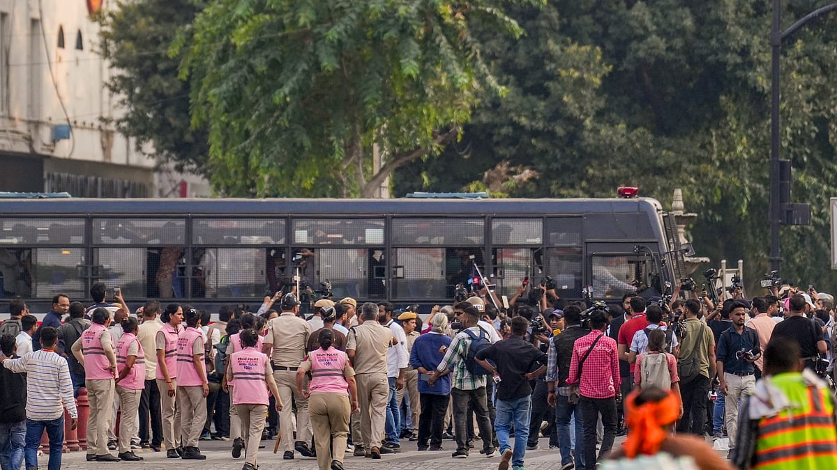Security personnel and media surround a bus carrying detained protesters in New Delhi.