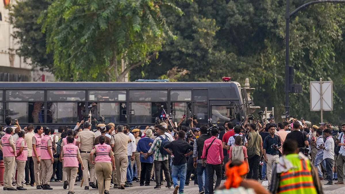 Media personnel gather around a police bus carrying detained protesters in New Delhi.