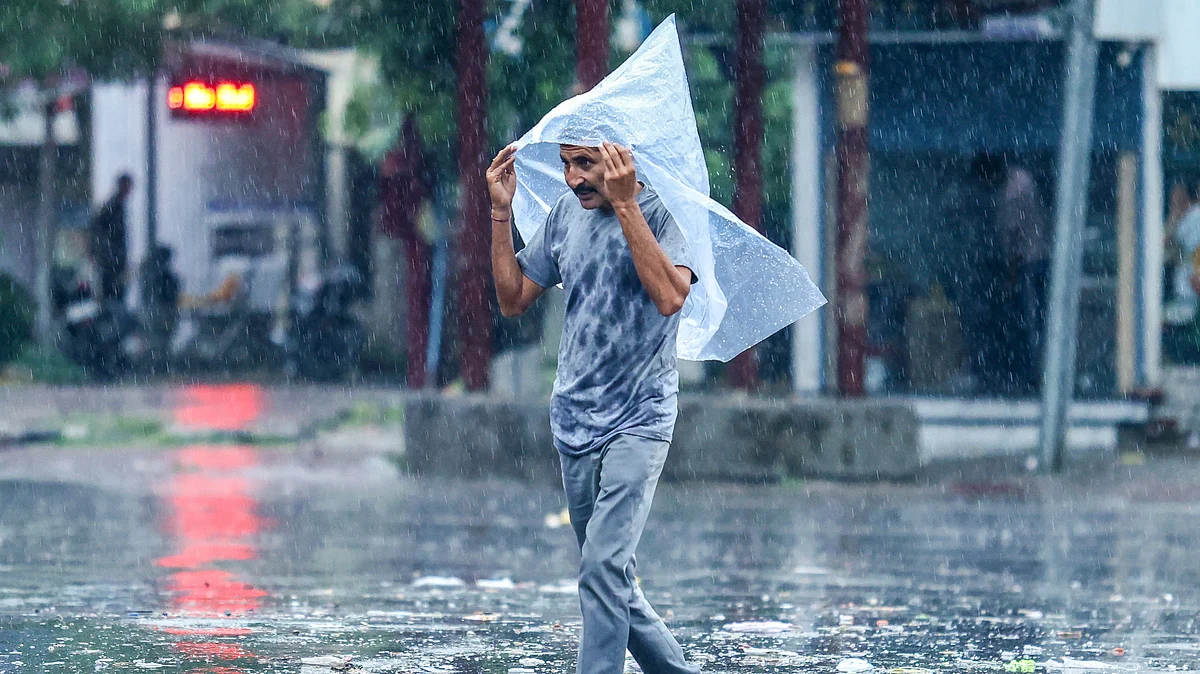 A man shields himself from heavy rainfall amid wet weather conditions.