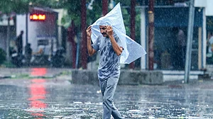 A man shields himself from heavy rainfall amid wet weather conditions.