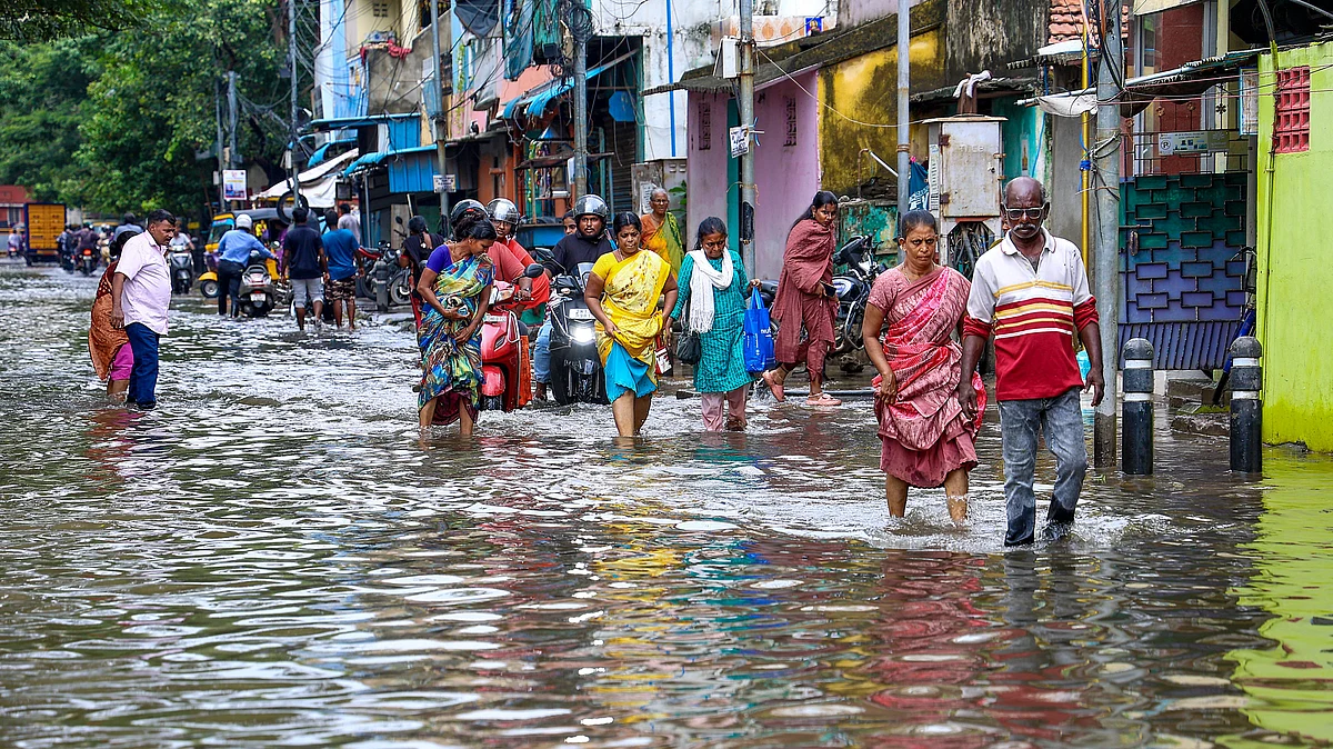 People wade through a waterlogged street in Chennai on 18 October