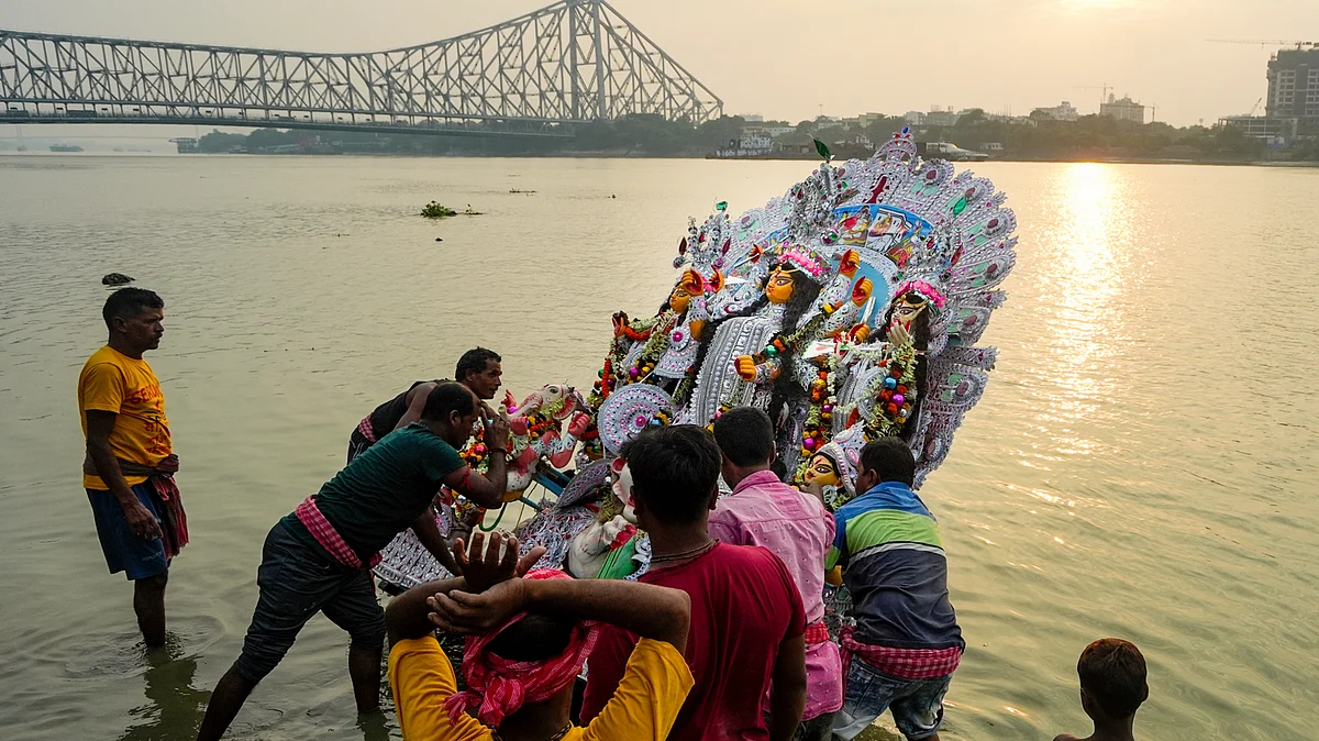 People immerse a Durga idol in the Hooghly river in Kolkata, 21 Oct