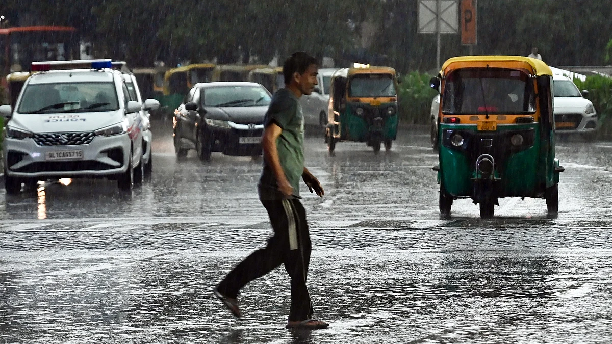 Vehicles navigate rain-soaked roads amid heavy rainfall in Delhi.