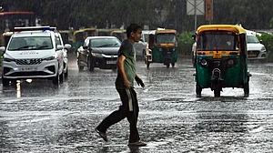 Vehicles navigate rain-soaked roads amid heavy rainfall in Delhi.