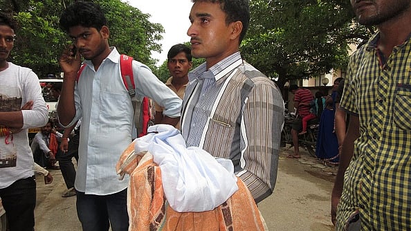 गोरखपुर के बीआरडी अस्पताल में मासूम का शव ले जाते परिजन / फोटो : Getty Images