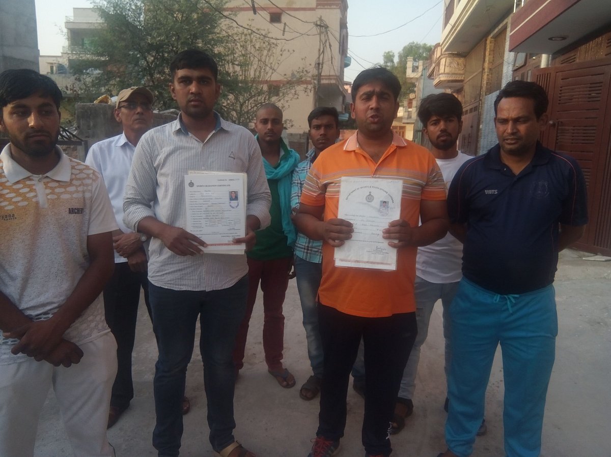 खेलों में पदक जीतने वाले युवा अपने सर्टिफिकेट दिखाते हुए
