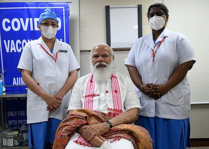कोरोना वैक्सीन लेने में भी पीएम मोदी ने दिया चुनावी संदेश, केरल-पुडुचेरी की नर्स से असम का गमछा पहनकर लिया टीका