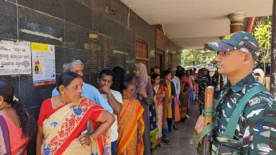 कर्नाटक चुनाव में मतदान के लिए एक बूथ पर लाइन में लगे वोटर