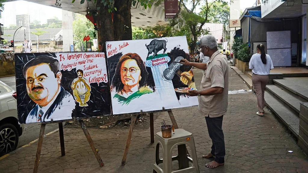 सेबी अध्यक्ष माधबी पुरी पर हिंडनबर्ग की रिपोर्ट आने के बाद मुंबई में एक स्कूली शिक्षक चित्र बनाता हुआ (फोटो : Getty Images)