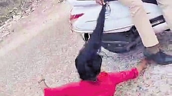 A videograb showing the protestor being dragged by cops on a two-wheeler.