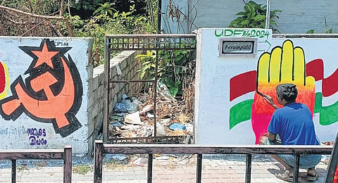 Representative Image: A UDF worker paints the graffiti of the Congress next to a wall displaying the LDF’s election symbol.