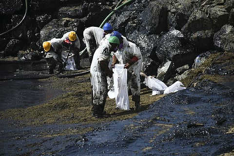 Workers from state owned Heritage Petroleum Oil and Gas Company clean up an oil spill that reached Rockly Bay Beach, Feb 11, 2024.