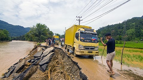  A man guides a truck along an erosion-damaged road following flash flooding in Pesisir Selatan Regency, West Sumatra.