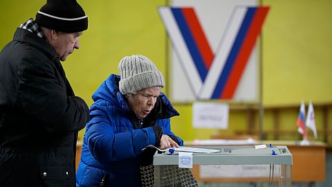 An elderly couple examine a ballot at a pooling station located in the school gymnasium during a presidential election in St. Petersburg, Russia. 