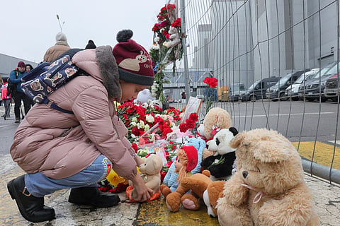 A child places a toy at the fence next to the Crocus City Hall, on the western edge of Moscow, Russia, Saturday, March 23, 2024, following an attack Friday, for which the Islamic State group claimed responsibility. 
