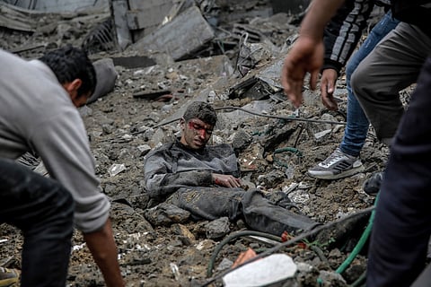 Palestinians rush to the aid of a wounded youth after Israeli bombardment in central Gaza City on March 18, 2024, amid the ongoing battles between Israel and the militant group Hamas.