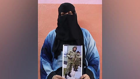 Mohammed's wife with a picture of Mohammed in military outfit. 