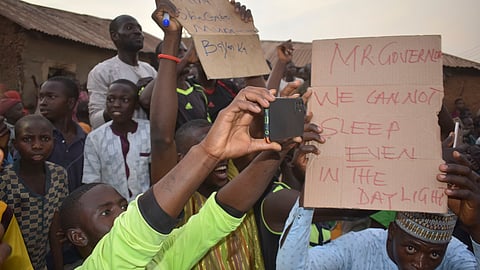 People gather around an area were gunmen kidnapped school children in Chikun, Nigeria, Thursday. 