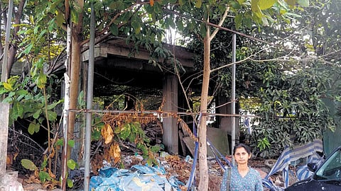 Suja Sebastian outside her plot, where a five-storey building lies unfinished