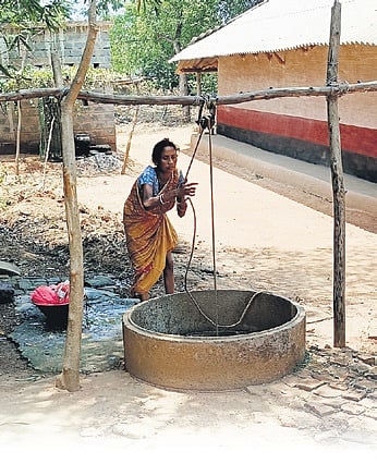A woman of Chaksuliapada village drawing water from a well