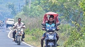 A pillion puts a towel over the head of a two-wheeler rider in Bhubaneswar 