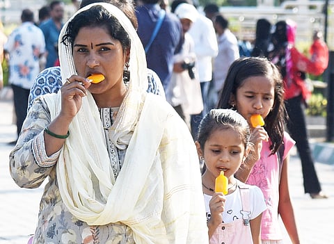 Women and children  walking by with ice candy on a hot summer afternoon in Bengaluru.