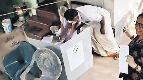 CPM leader E K Ganeshan interfering in the ‘vote from home’ procedure of 92-year-old Devi at Kalliasseri in the presence of polling officials on Thursday. 