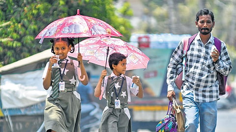 Students use umbrellas to protect themselves from the scorching heat in Vijayawada on Monday 
