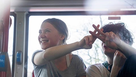 Climate activist Greta Thunberg flashes a V-sign after being detained and driven off in a bus after joining protestors who blocked a road during a climate protest of Extinction Rebellion.