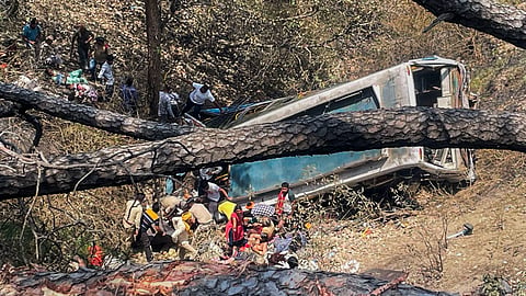 Police personnel and civilians near the wreckage of the bus which skidded off the road and fell into a gorge at Chowki Choura, in Jammu district, Thursday, May 30, 2024. At least 7 pilgrims were killed and 23 injured in the accident, according to officials. 