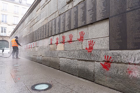 A city employee at work cleaning the "Wall of the Righteous" (Mur des Justes) covered with Red hands graffitis outside the Shoah memorial in Paris, after the monument was vandalized overnight. 