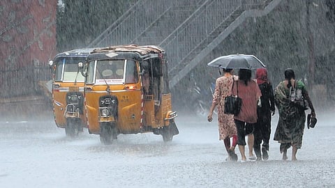 A group of women, left, brave the heavy rain that lashed Hyderabad in the late afternoon of Thursday 