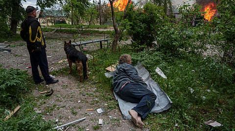 A man lies on the ground as he watches his burning house destroyed by a Russian airstrike in Vovchansk, Ukraine