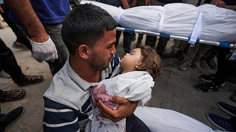 A Palestinian man holds the body of his 2-year-old daughter Sabreen, who was among 20 people, mostly women and children, killed in an Israeli airstrike in central Gaza. 