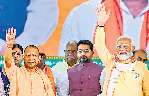 Prime Minister Narendra Modi with Uttar Pradesh Chief Minister Yogi Adityanath greets supporters during a public meeting in Basti on Wednesday .