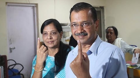 Delhi Chief Minister Arvind Kejriwal and wife Sunita Kejriwal show their fingers marked with indelible ink after casting vote in the Delhi Assembly elections