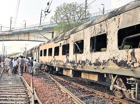 Passengers on track beside charred coaches after fire erupted on the Taj Express 