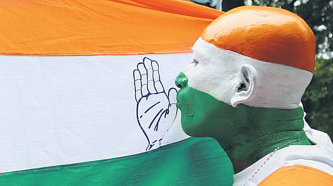 A Congress worker kisses the party flag while celebrating the party’s election victory in Kochi on Tuesday 