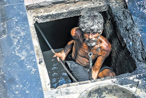 A worker seen clearing silt accumulated in drains in Vijayawada 